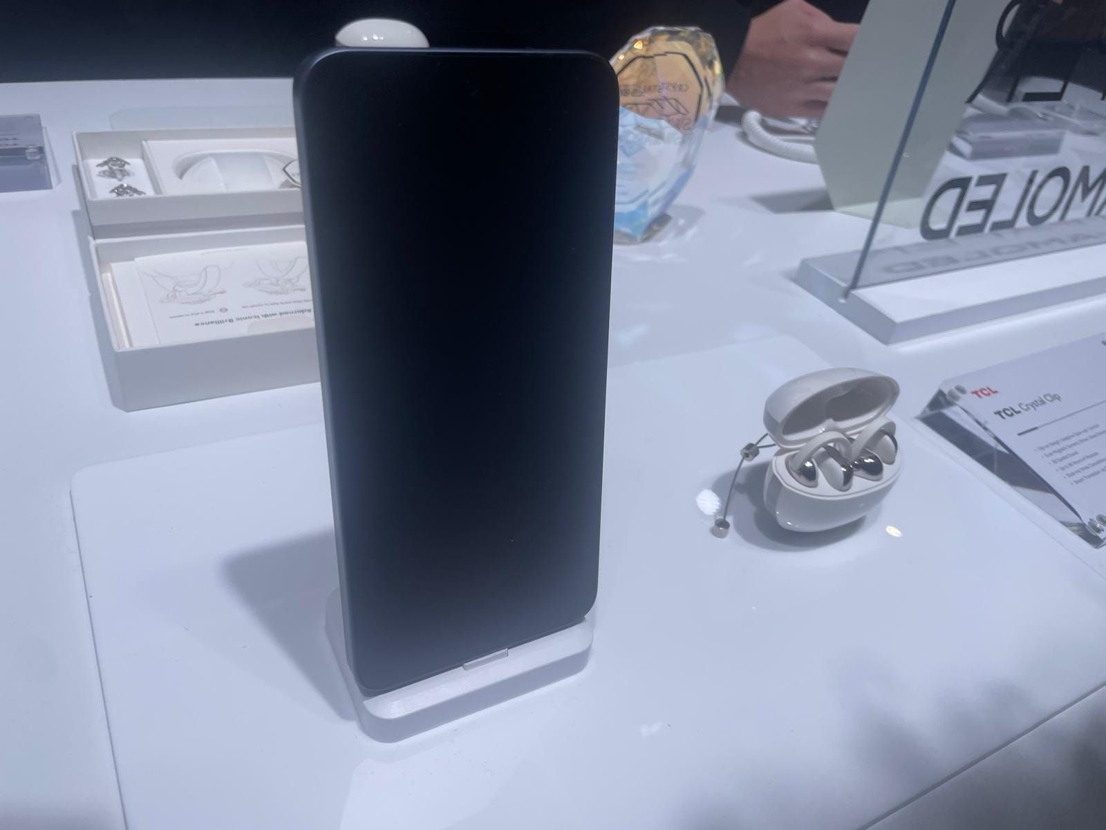 Fotografía de los auriculares TCL CrystalClip junto con un teléfono de la misma marca durante su presentación en el MWC 2026 de Barcelona